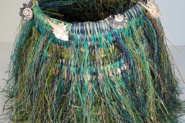 Blue and green woven basket with shells around the top of the basket.