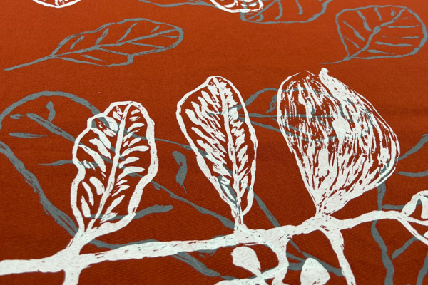 Red fabric with grey leaves printed on top and more plants printed in white over the top.