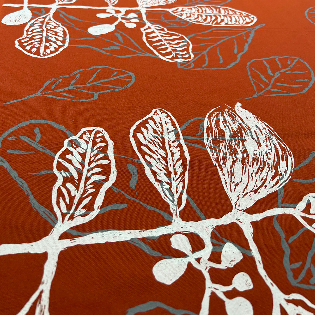 Red fabric with grey leaves printed on top and more plants printed in white over the top.
