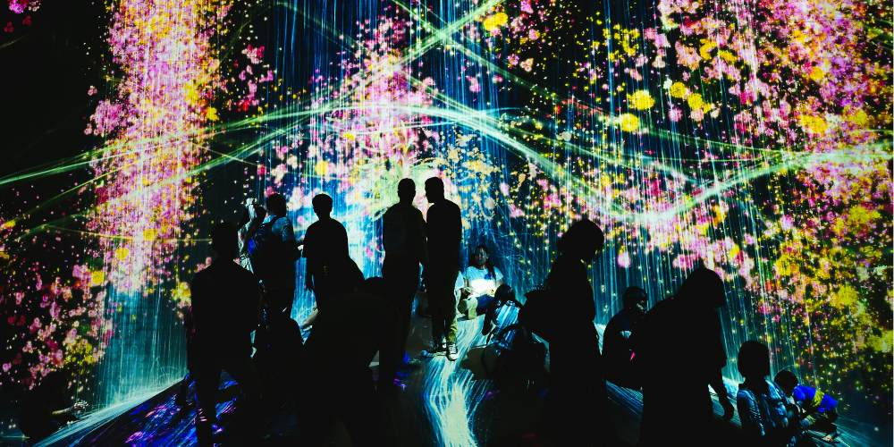 silhouette of people standing in front of brighly coloured projection image